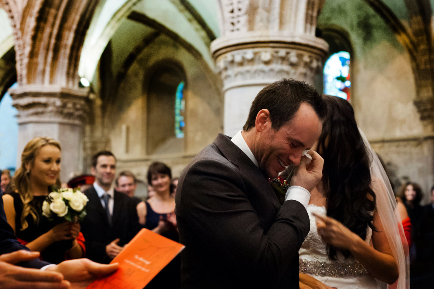 Groom dabbing eyes during wedding ceremony 