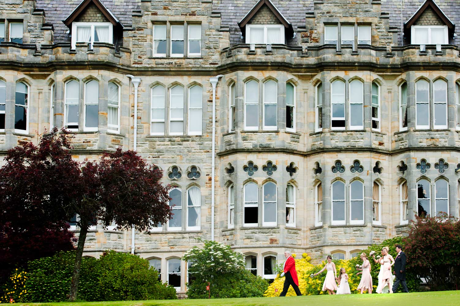 Bridal party walking through grounds of the Ashdown Park hotel 