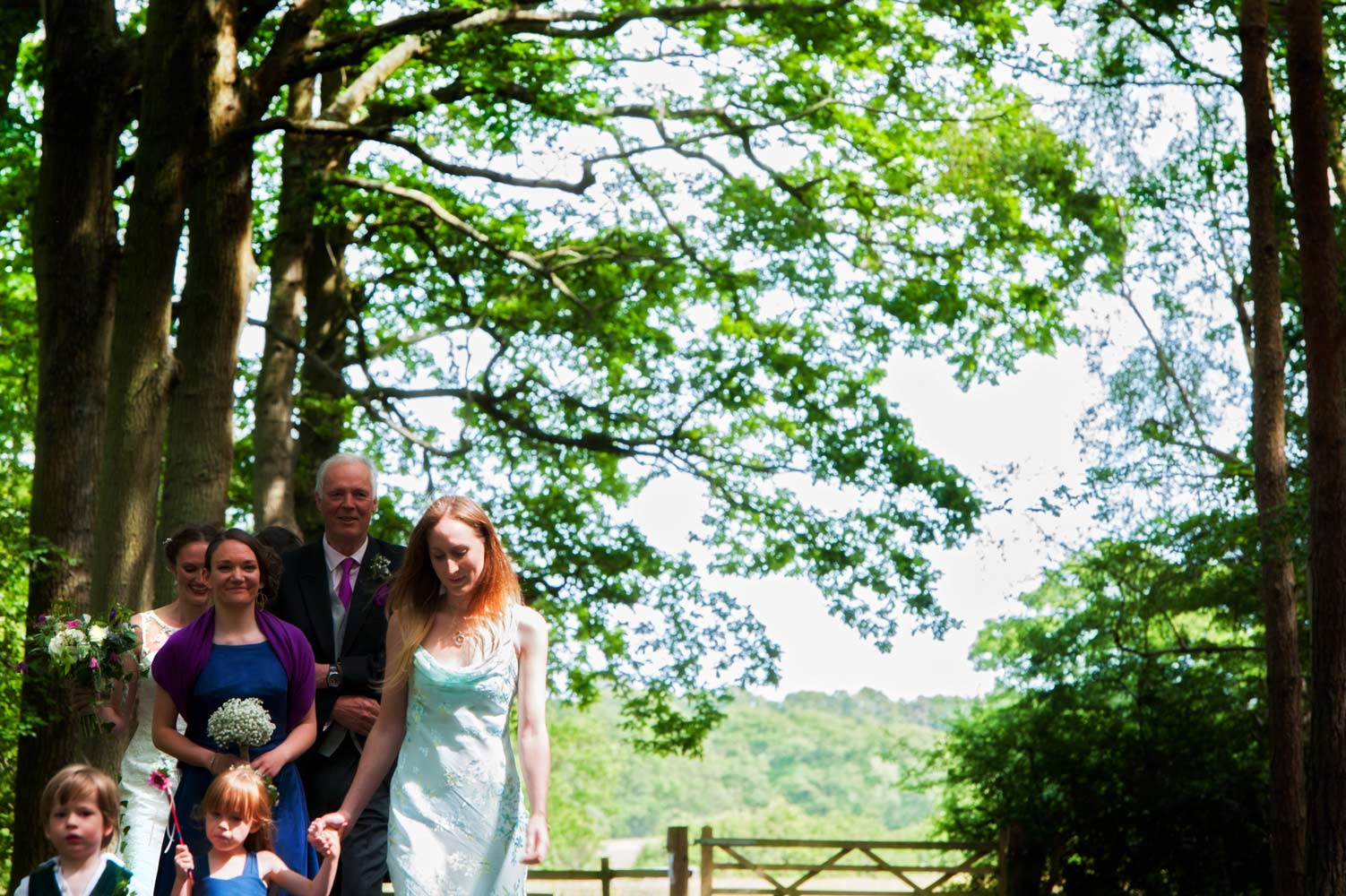 Bridal party walking through woods by Sussex reportage photographer James Robertshaw