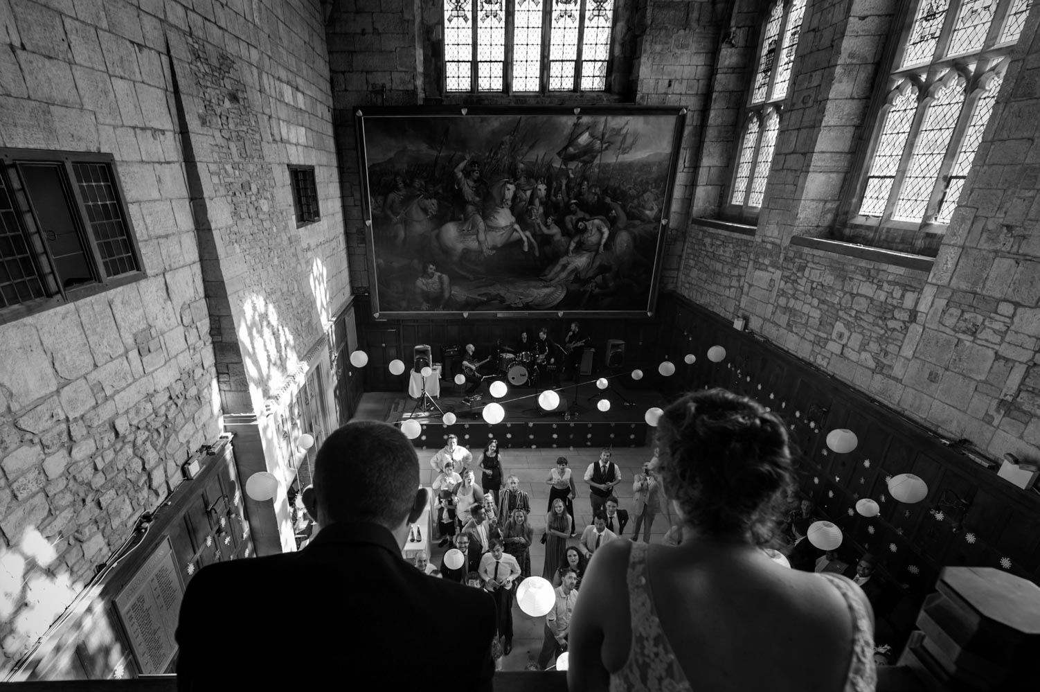 Wedding couple looking down over guests from balcony