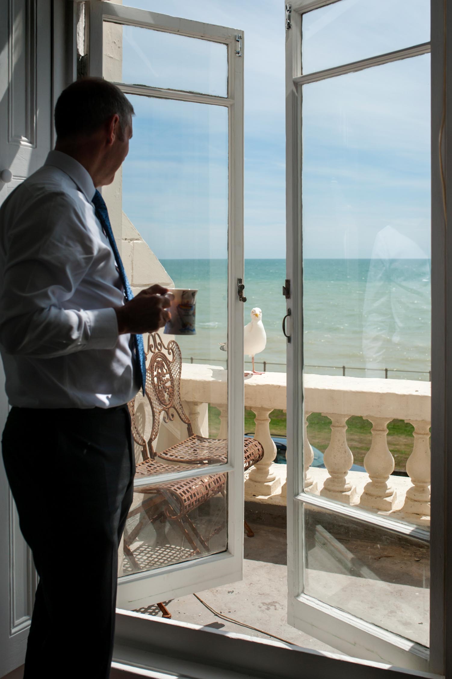 Groom looking at seagull on balcony by informal Sussex wedding photographer James Robertshaw 