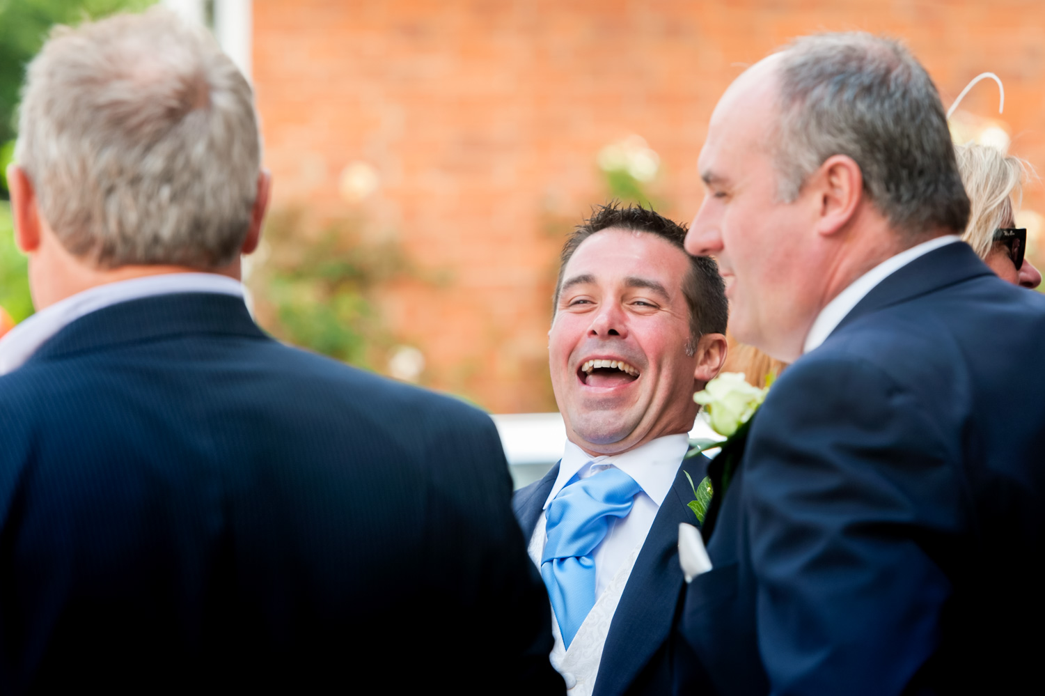 Groom laughing with friends by Sussex documentary photographer James Robertshaw