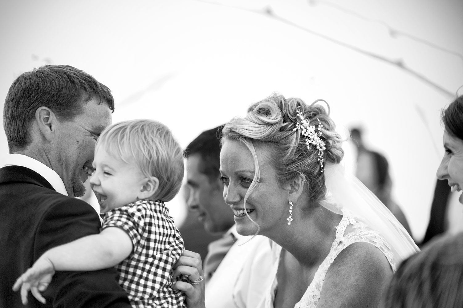 Bride tickling child at wedding reception by Sussex documentary wedding photographer James Robertshaw 