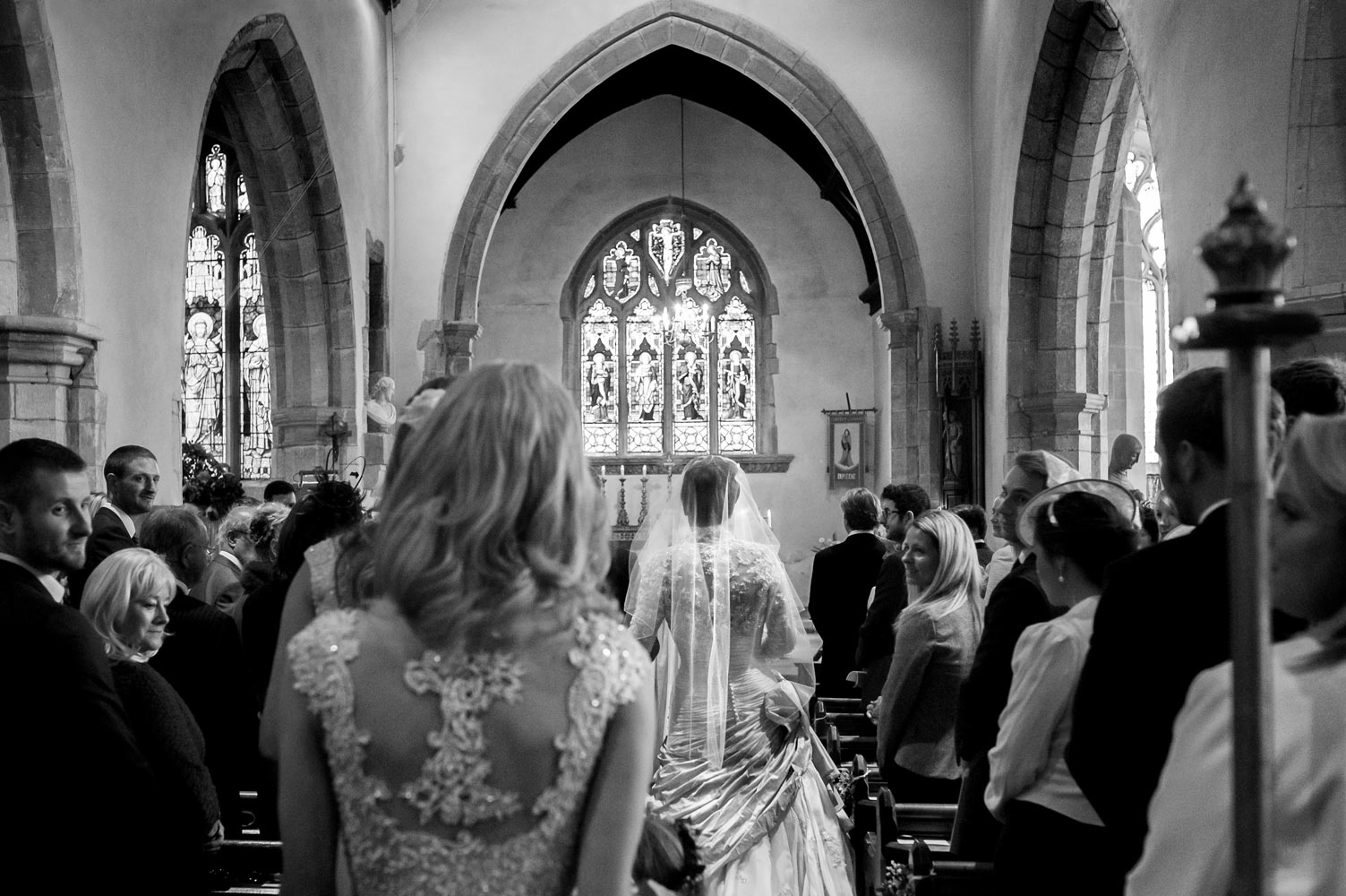 Bride and bridesmaids walking down the aisle in church by east Sussex wedding photographer James Robertshaw