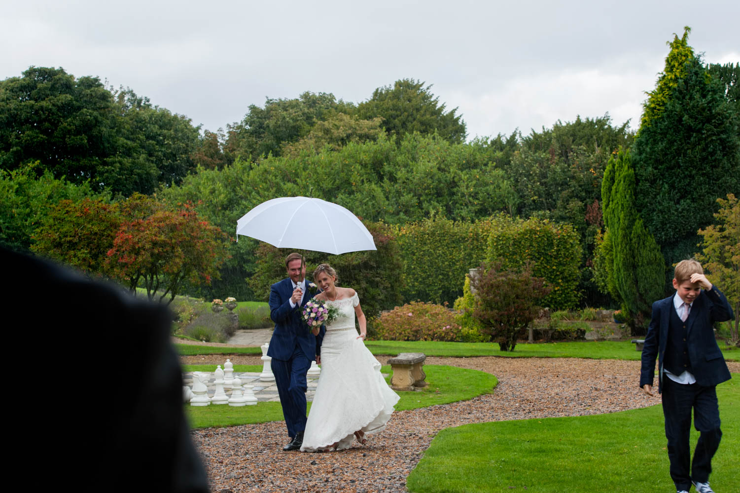 Bride and grrom with umbrella in gardens