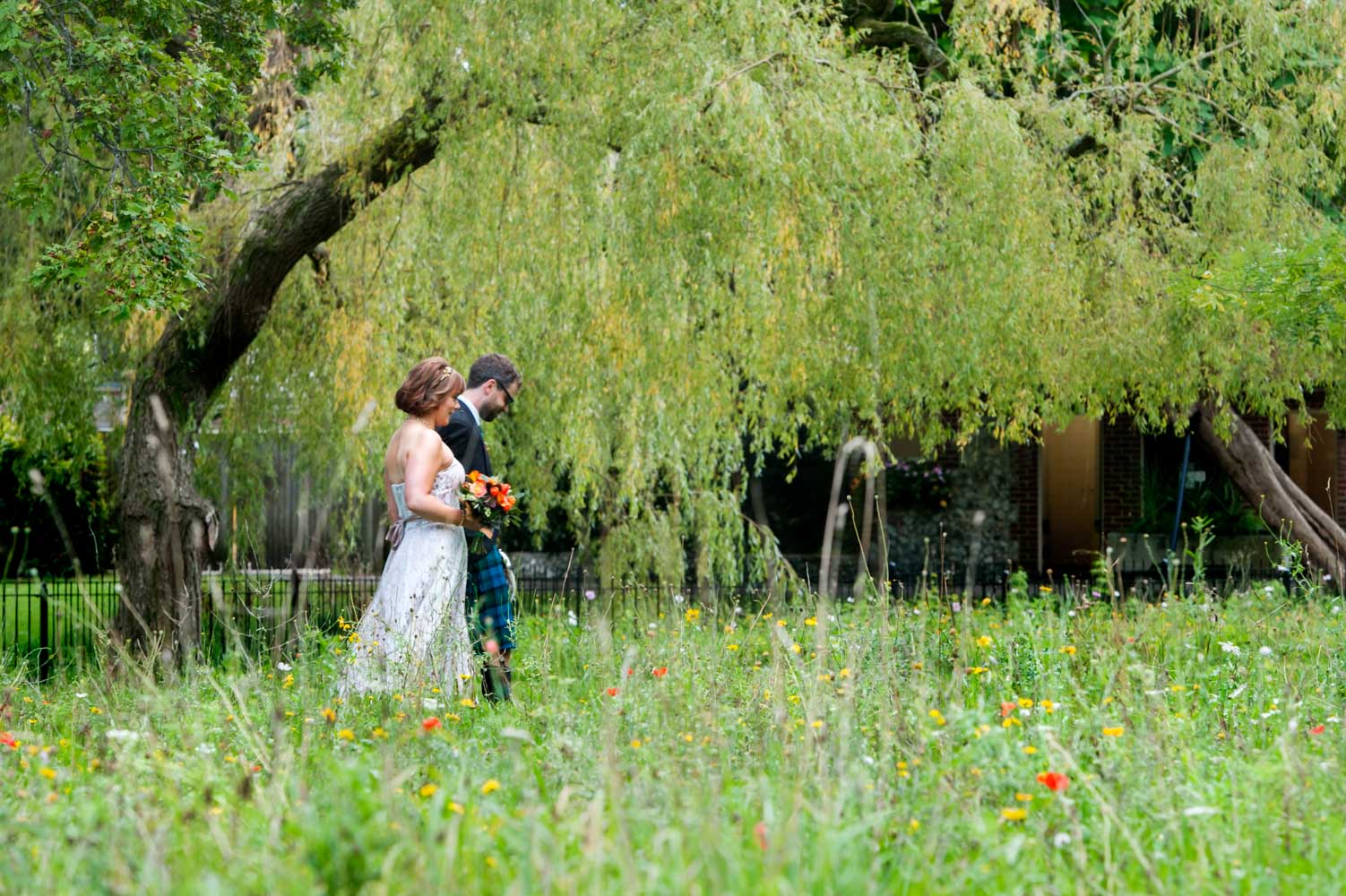 Newly married couple walking through garden