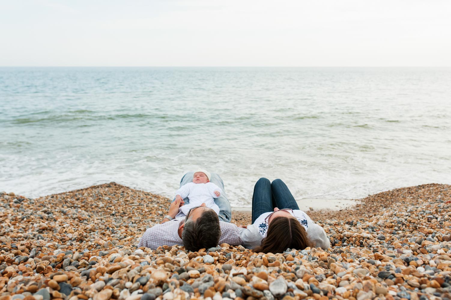 Couple lying on the beach with baby