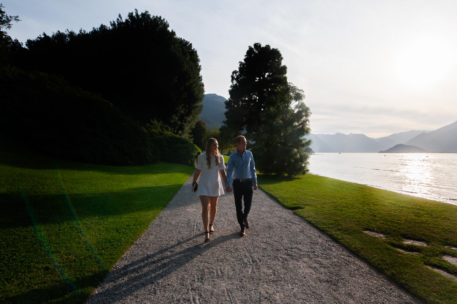 Engaged couple walking beside lake Como