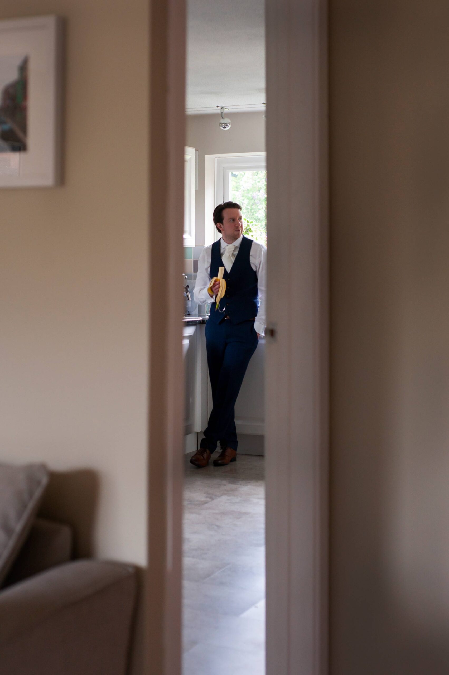 Groom eating a banana on morning of wedding by West Sussex wedding photographer James Robertshaw.