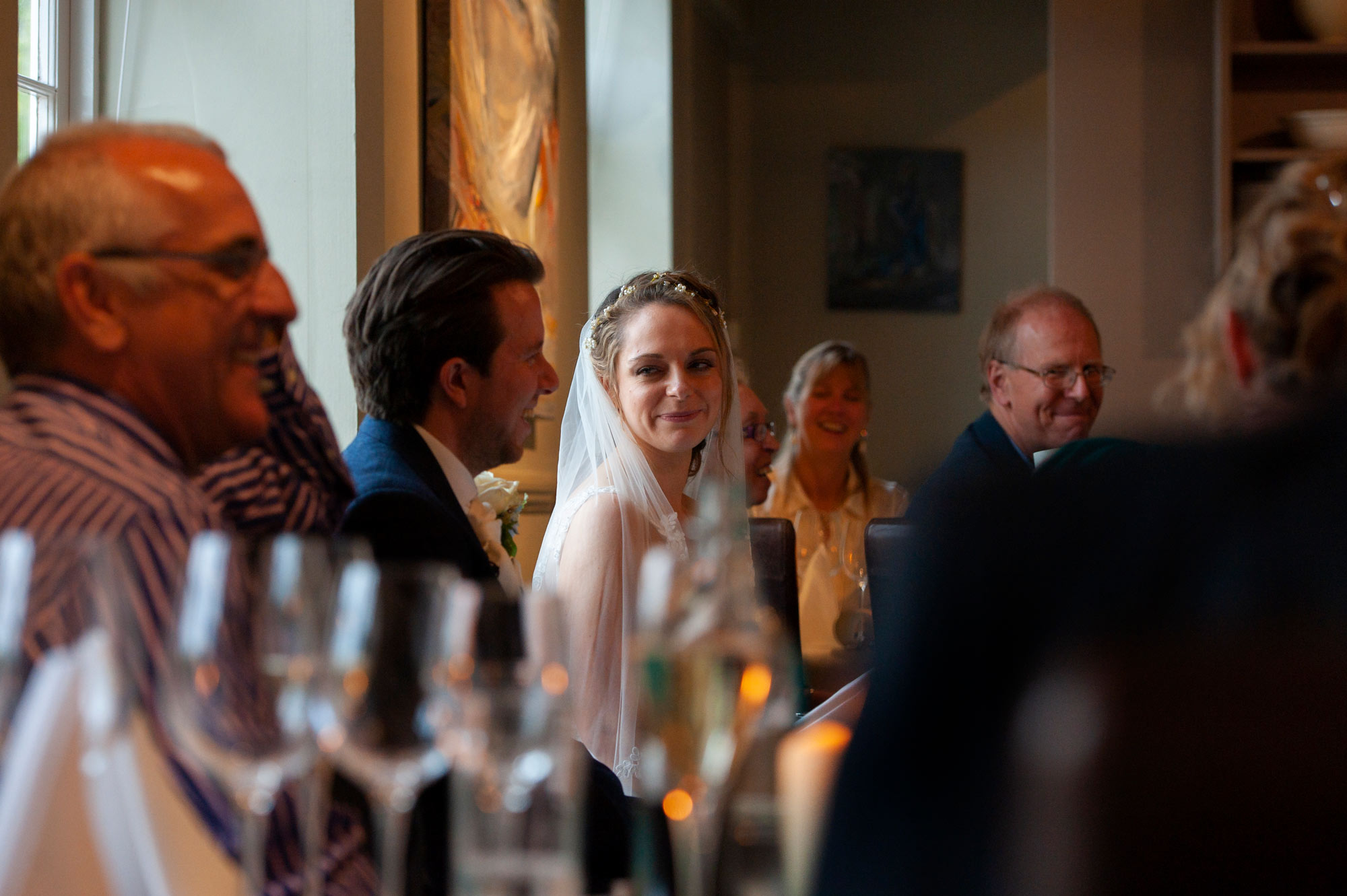 Bride and groom seated and laughing  during speeches at Jeremy's Restaurant, Haward's Heath.