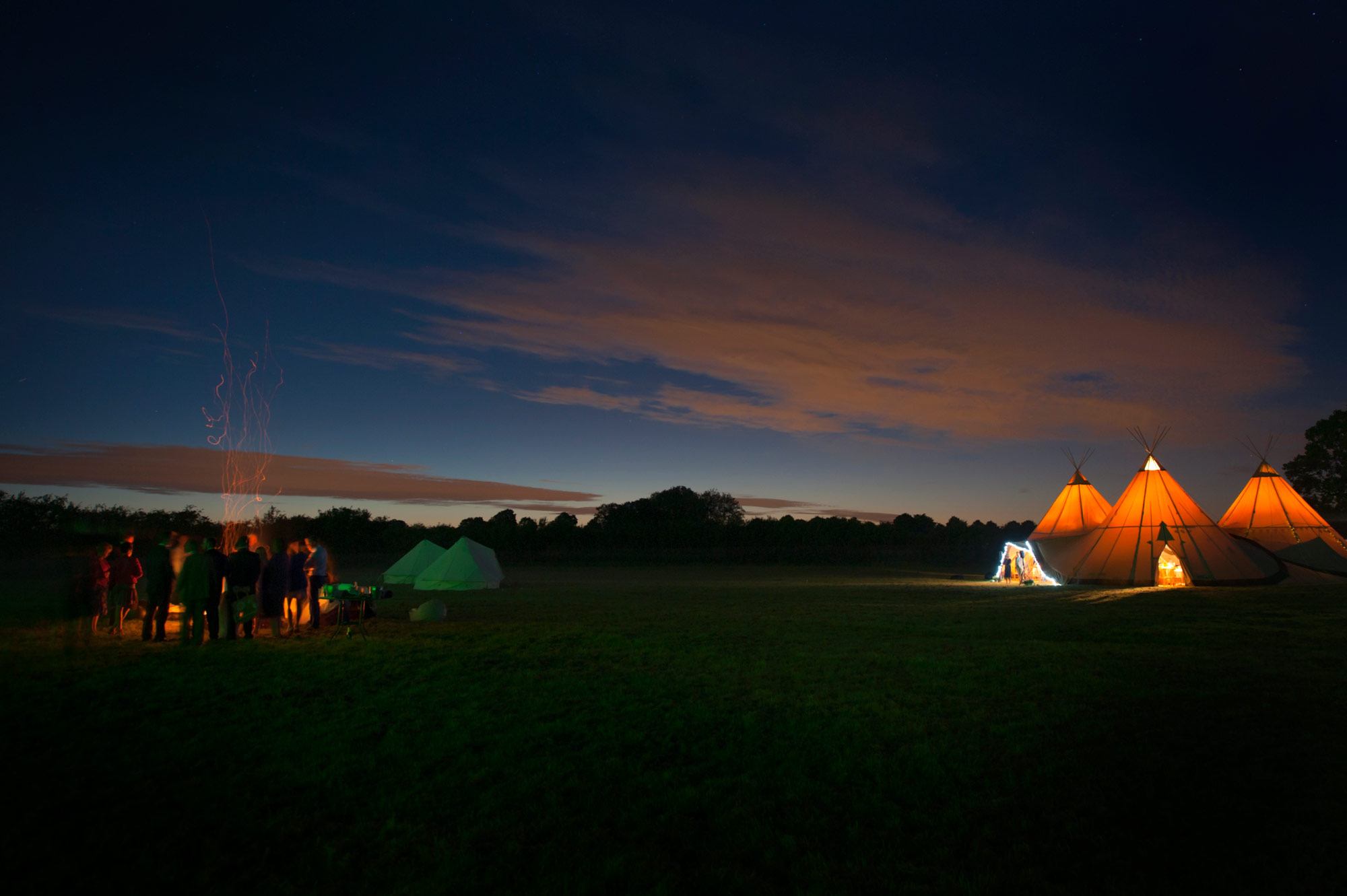 Tee pees and bonfire after dark at outdoor wedding to illustrate Sussex wedding photogrpaher reviews