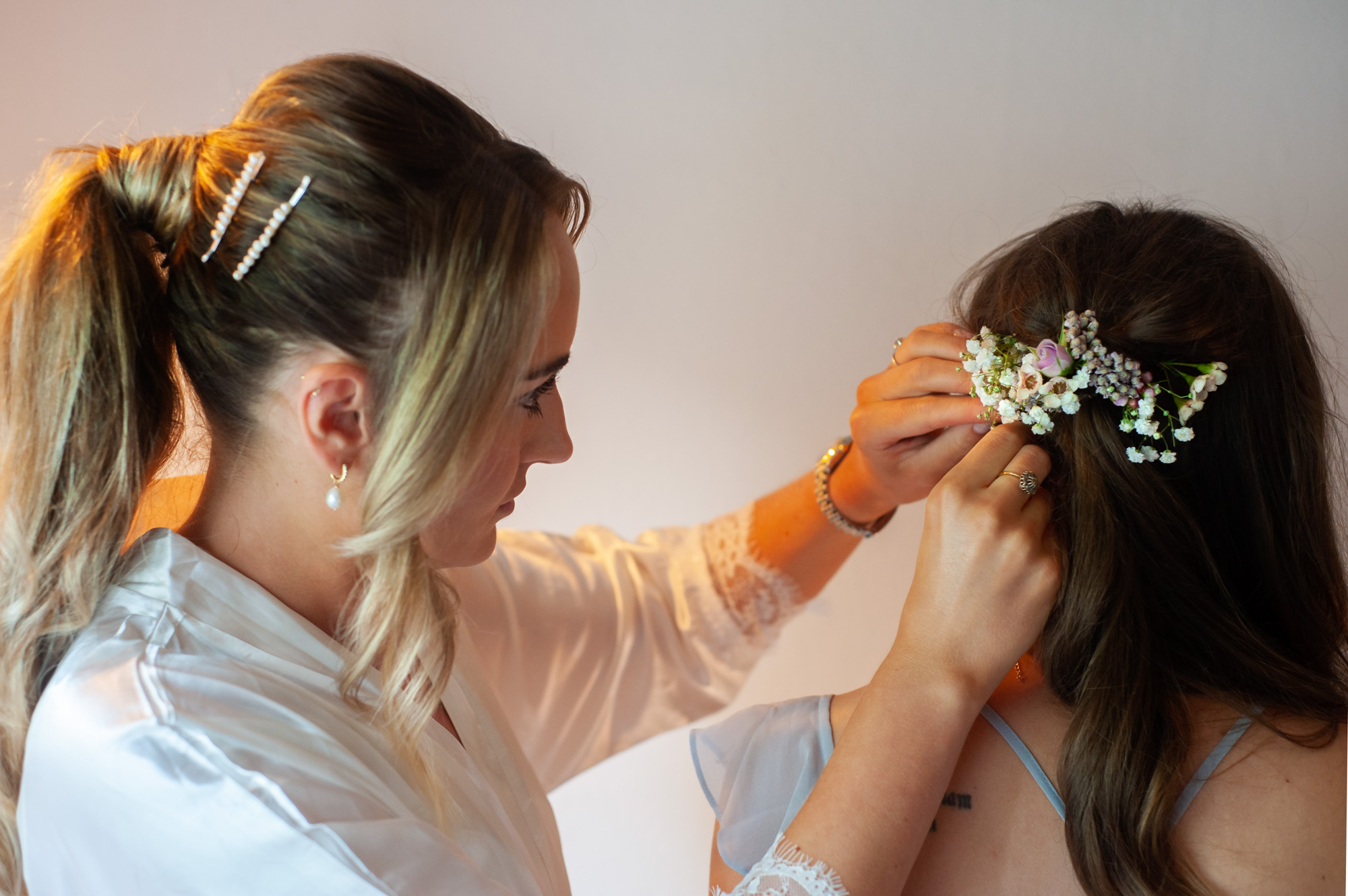 Bride attaching hairclip to bridesmaid. Image by East Sussex documentary wedding photographer James Robertshaw.