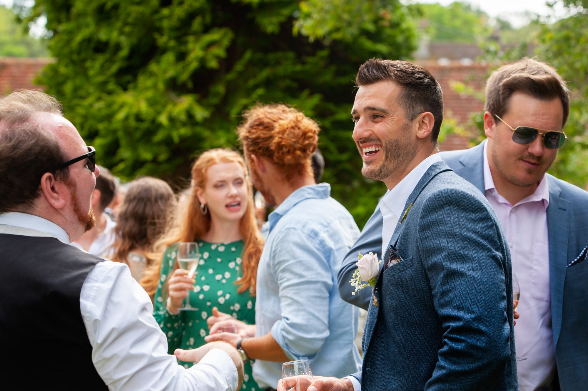 Groom smiling at outdoor wedding reception.