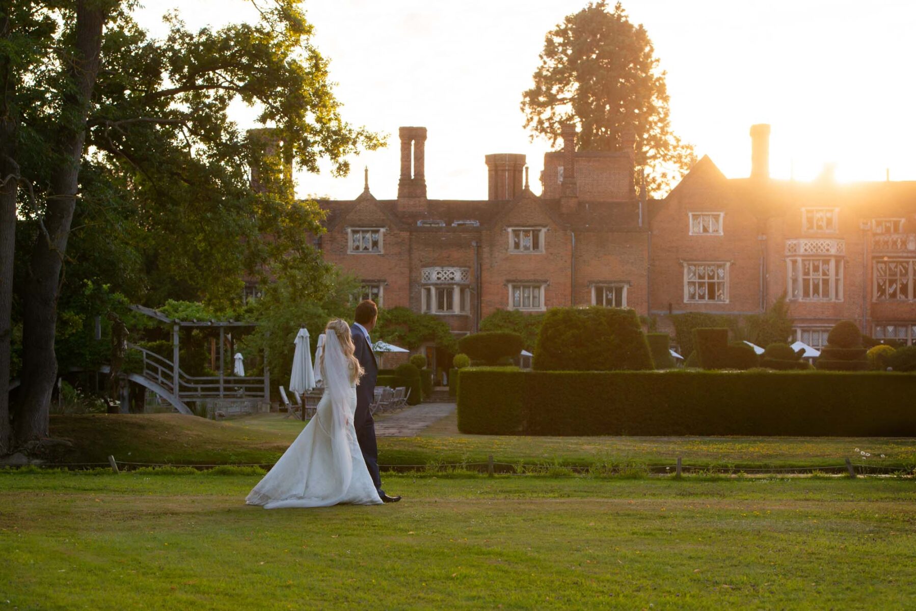 Couple walking in the grounds of Great Fosters after wedding